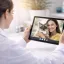 Vet in a white coat on a video consultation on a tablet with a woman holding her cat in her arms